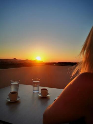 a woman sitting at a table watching the sunset at Κallisto rooms in Mytakas