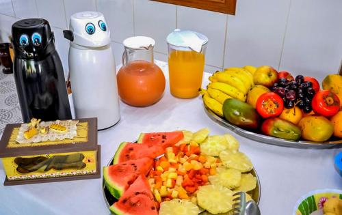 a table topped with a plate of fruit and juice at VOA Pousada Dos Jasmins in Serra