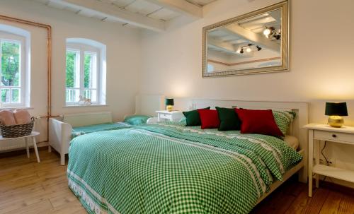 1 dormitorio con 1 cama con almohadas verdes y rojas en Vidéki vendégház Szögliget, en Szögliget