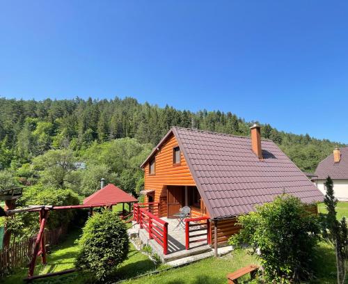 a wooden house with a red fence and trees at Chata Zahura in Spišské Vlachy