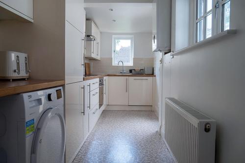 a small white kitchen with a washer and a sink at cosy and peaceful near Ashford town centre in Kent
