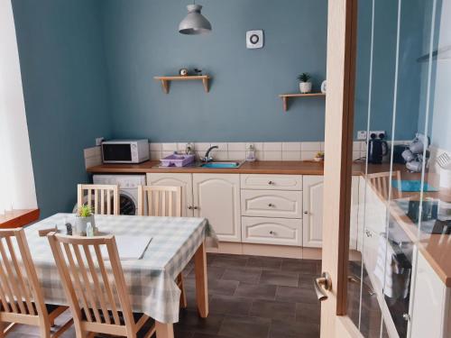 uma cozinha com uma mesa e cadeiras e uma parede azul em No.4 Bignold em Wick