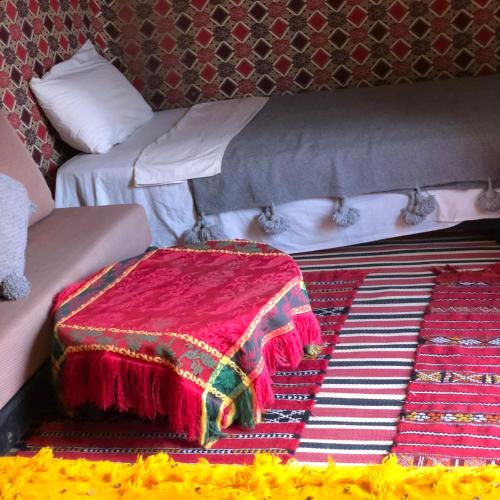 a bed with a red blanket on top of it at Erg Chegaga Camp & Activites in Mhamid