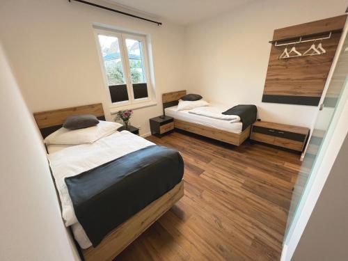 two beds in a room with wooden floors at Konrads Pension in Solms-Oberbiel