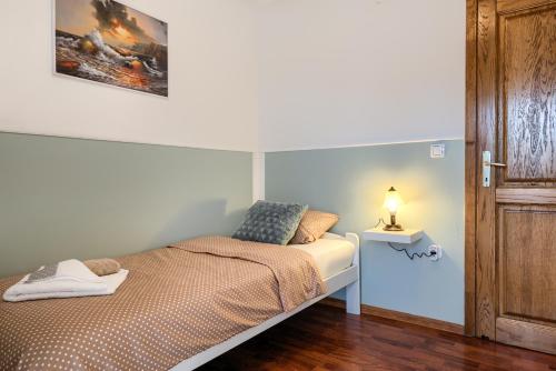 a small bedroom with a bed and a lamp on a table at Apartmani Plavi val in Vodnjan
