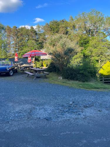 einen Picknicktisch mit einem roten Regenschirm und einem Auto in der Unterkunft The Mill Inn in Penrith