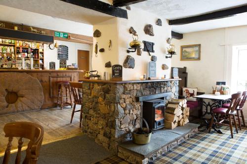 a room with a stone fireplace and a bar at The Mill Inn in Penrith