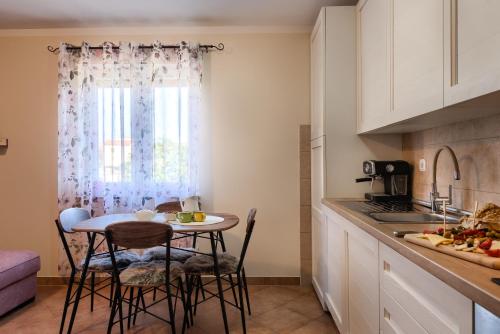 a kitchen with a table and chairs and a window at Apartmani Plavi val in Vodnjan