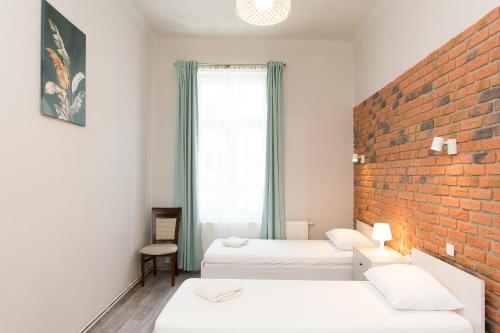 a room with two beds and a brick wall at Mariacki Church 3-ROOMS p4you pl in Krakow