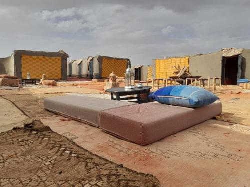a large bed sitting on the ground in front of tents at Erg Chegaga Camp & Activites in Mhamid
