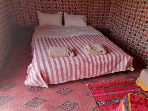a red and white bed with two towels on it at Erg Chegaga Camp & Activites in Mhamid