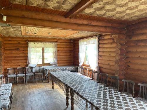 une chambre avec des tables et des chaises dans une cabane en rondins dans l'établissement Brīvdienu māja “Dzirnavnieki”, à Bauska