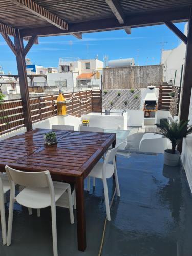 a wooden table and white chairs on a patio at Different House Holidays in Fuzeta