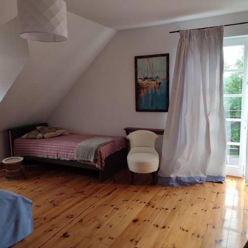 a bedroom with a bed and a chair and a window at Apartament Urocze miejsce in Kazimierz Dolny