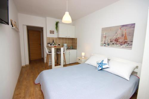 a bedroom with a white bed and a kitchen at Apartments Nina in Cavtat