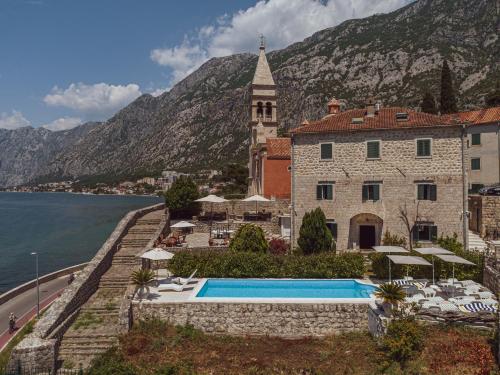 un edificio con una piscina junto a un cuerpo de agua en Kamena Palata Apartments, en Kotor