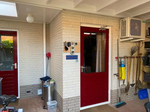 un muro di mattoni con una porta rossa e una rossa di La Nuova Casa del Campo (vh De Kamp) a Dinxperlo