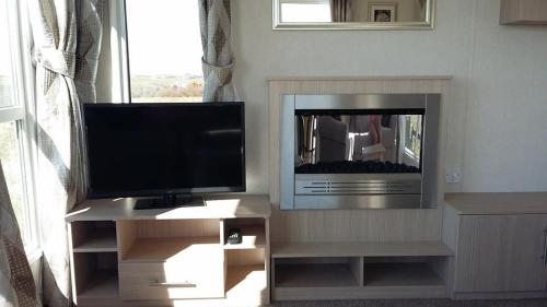 a flat screen tv sitting on a entertainment center at Golden Burn Cottage Caravan in Padstow