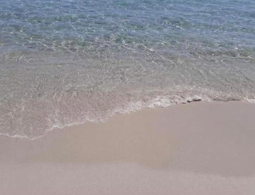 a beach with the ocean and the sand and water at La perla del mare in La Caletta