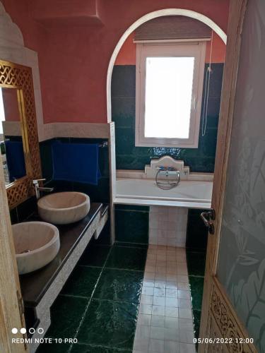 a bathroom with two sinks and a tub and a window at La superbe villa à Kélibia la blanche in Kelibia