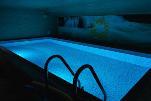 een zwembad met blauwe verlichting in een kamer bij Zagroda Nad Kotelnią in Pawłowa