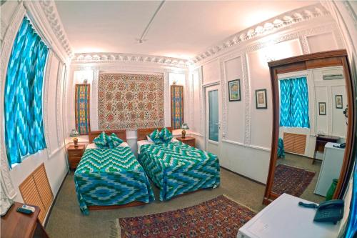 um quarto com 2 sofás e um quarto com cortinas azuis em Minzifa Inn em Bukhara