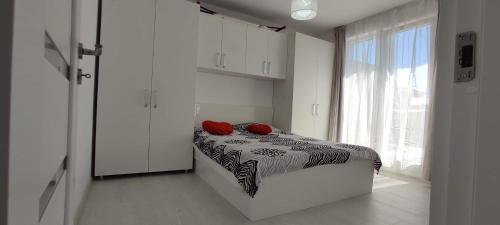ein Schlafzimmer mit einem Bett mit zwei roten Kissen darauf in der Unterkunft Julia's Residence in Cisnădie