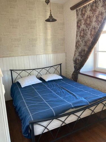 een slaapkamer met een bed met blauwe lakens en een raam bij Saue 10 in Haapsalu