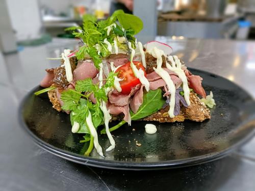a sandwich with meat and salad on a black plate at Boutique Hotel, Restaurant & Wellness Westerburcht in Westerbork