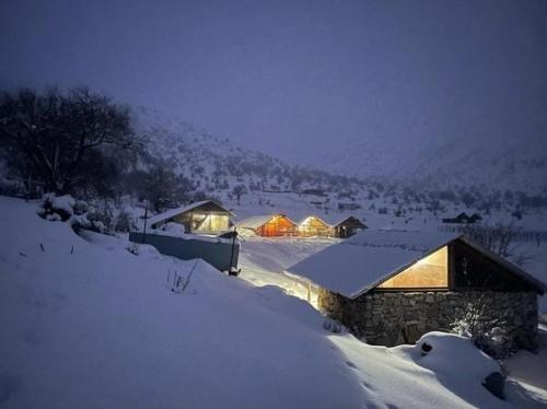 una casa cubierta de nieve con luces encendidas en Camping Cajupi, en Gjirokastra
