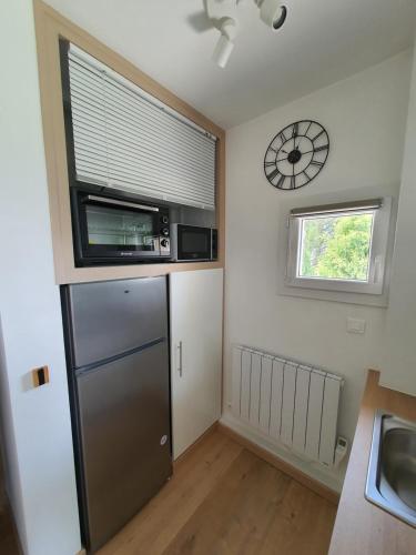 Il comprend une cuisine équipée d'un réfrigérateur et d'une horloge murale. dans l'établissement Studio lumineux au calme, vue sur le parc, à Gréoux-les-Bains