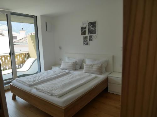 uma cama com lençóis brancos e almofadas num quarto em Appartement Baumgärtner em Naturno
