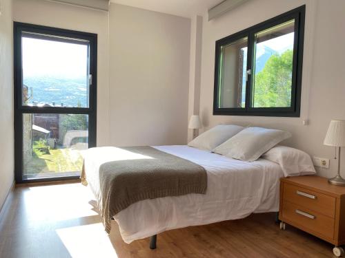 um quarto com uma cama grande e 2 janelas em La Portella em Pauls de Flamisells
