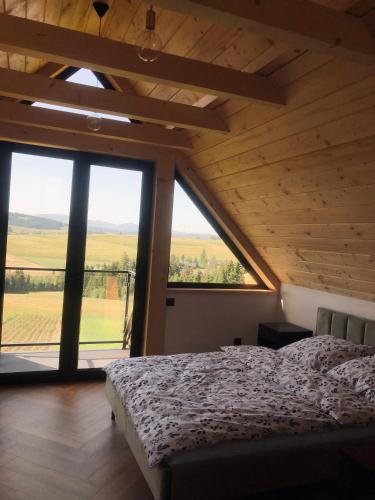a bedroom with a bed and a large window at Czarne Jodły in Jabłonka