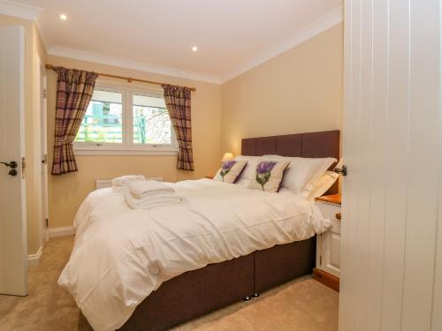 a bedroom with a bed with white sheets and a window at The Lodge in Blairgowrie