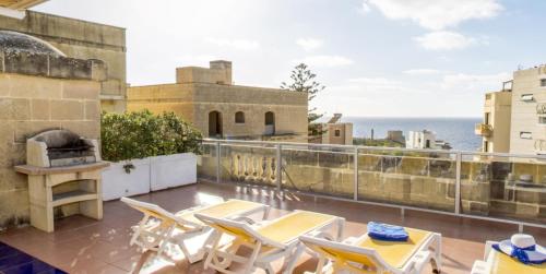 a balcony with tables and chairs and the ocean at Villa Xemxija in Xlendi