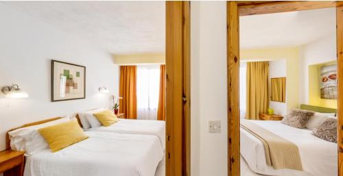 a bedroom with two beds with white sheets and yellow pillows at Villa Xemxija in Xlendi