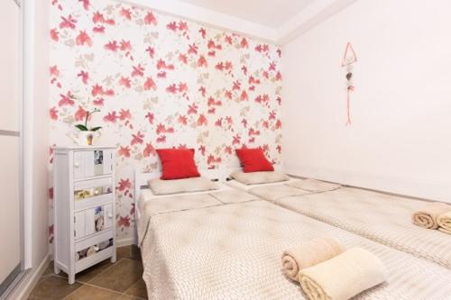 een slaapkamer met twee bedden met rode en witte bloemen aan de muur bij Apartman studio Sanja Klimno in Klimno