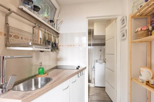 een keuken met witte kasten en een wastafel bij Apartman studio Sanja Klimno in Klimno