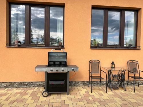 a grill with two chairs and a table and a building at Tři okna do hor-Celý byt k pronájmu in Rýmařov