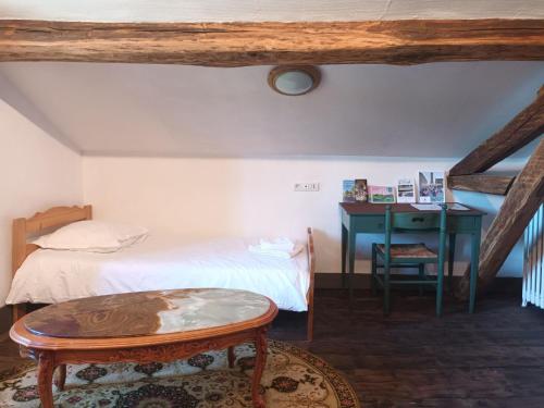 une chambre avec un lit, une table et un bureau dans l'établissement Chambres d'hôtes Le Veilleur de Noblat, à Saint-Léonard-de-Noblat