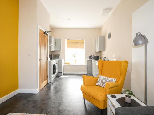 a living room with a yellow chair and a kitchen at Moel Tryfan in Caernarfon