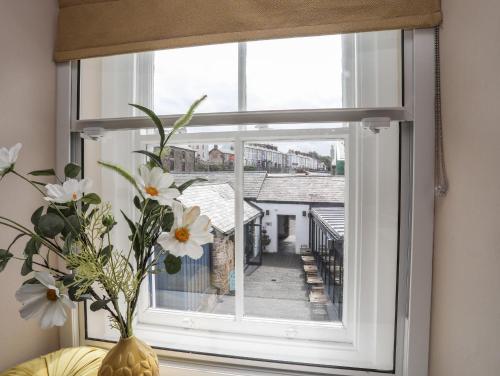 a window with white flowers in a vase on a table at Moel Tryfan in Caernarfon