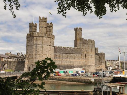 a castle with two towers and a body of water at Moel Tryfan in Caernarfon