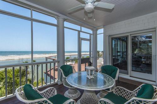 a balcony with a table and chairs and the beach at Lookout Point in Edisto Island