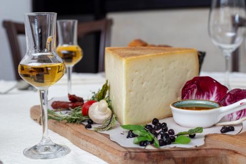 a piece of cheese and a glass of wine on a table at Adoro Titova Vila in Zlatibor