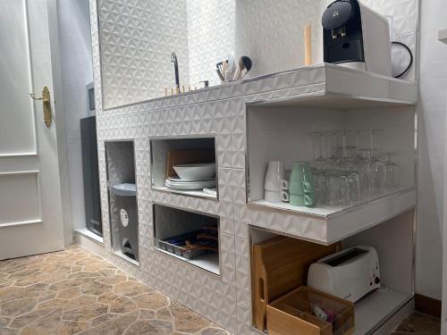 a kitchen with white shelves with plates and dishes at Casa Arequipa in Vejer de la Frontera