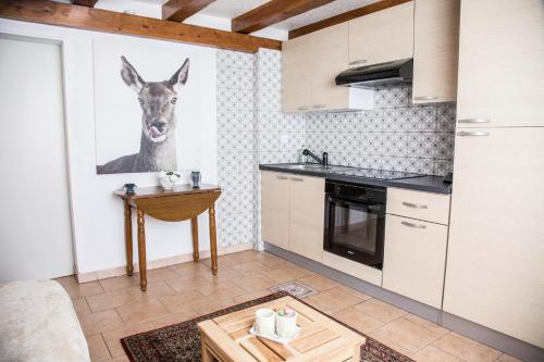 a kitchen with a painting of a deer on the wall at les hortensias La Souris Des Champs in Étival-Clairefontaine