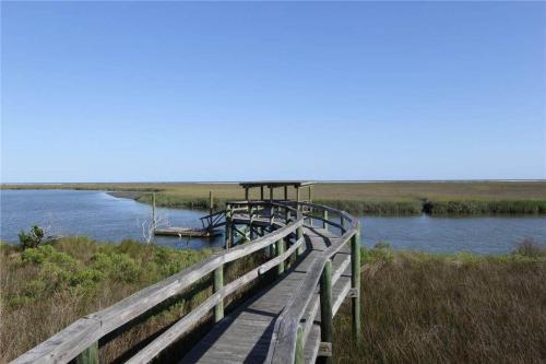 a wooden bridge over a river with a boat on it at Whitmarsh in Edisto Island
