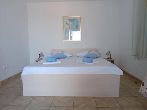 Una cama blanca con almohadas azules en una habitación blanca en Apartments Katarina, en Podstrana